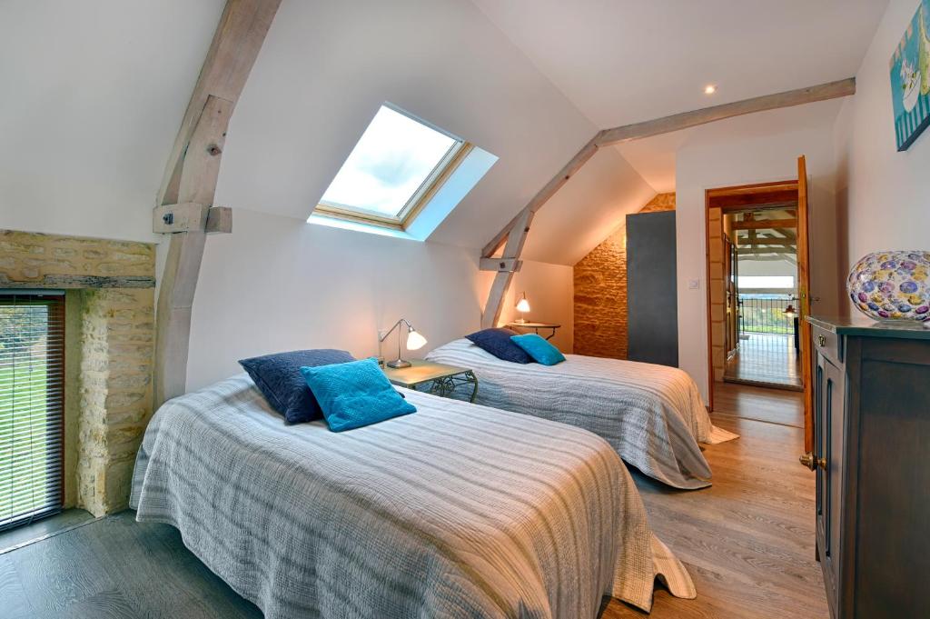 une chambre avec deux lits et une lucarne dans l'établissement Le Domaine du Douet du Houle, Piscine & SPA, 2-19p, à Courcy