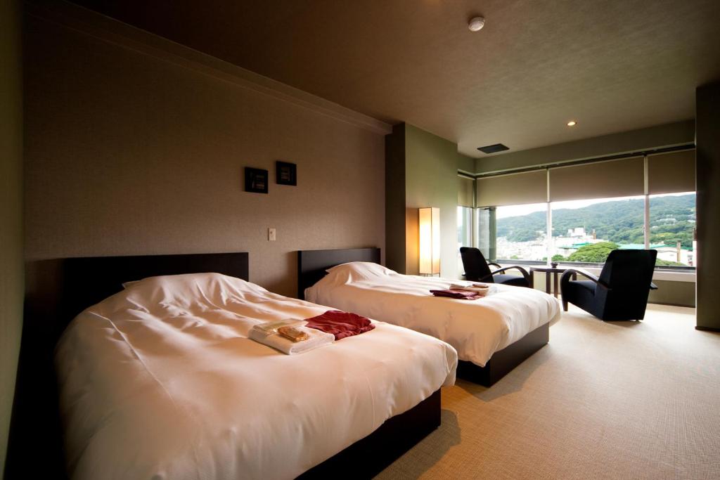 une chambre d'hôtel avec deux lits et une fenêtre dans l'établissement Ito Yukitei, à Itō 37 autres photos