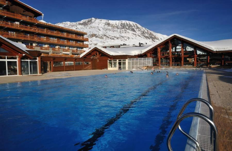 - une piscine en face d'un bâtiment avec une montagne dans l'établissement Résidence Les Mélèzes, à L'Alpe-d'Huez