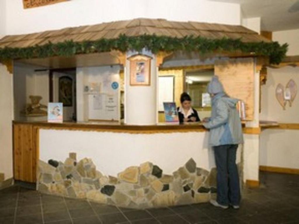 une personne debout au comptoir d'un bâtiment avec un faux dans l'établissement Résidence Les Mélèzes, à L'Alpe-d'Huez