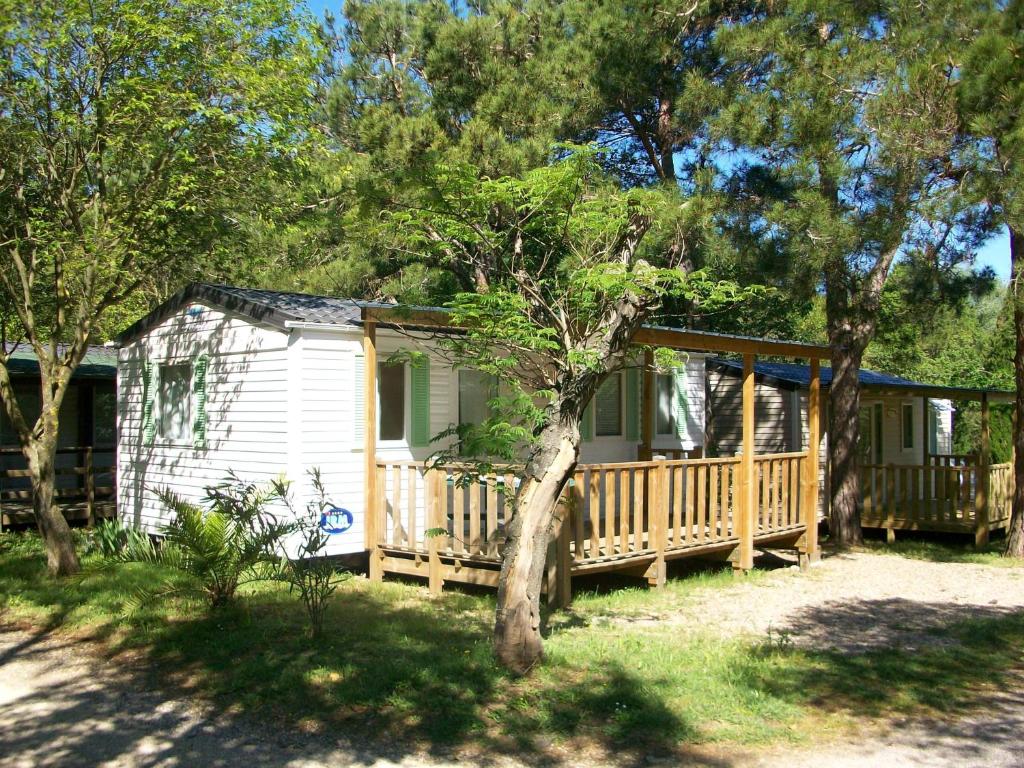 une petite maison blanche avec une véranda et des arbres dans l'établissement Camping de la Chapelette, à Saint-Martin-de-Crau