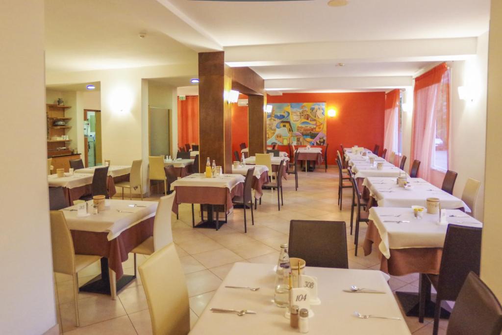 une salle à manger avec des tables et des chaises blanches dans l'établissement Hotel Nederland, à Caorle