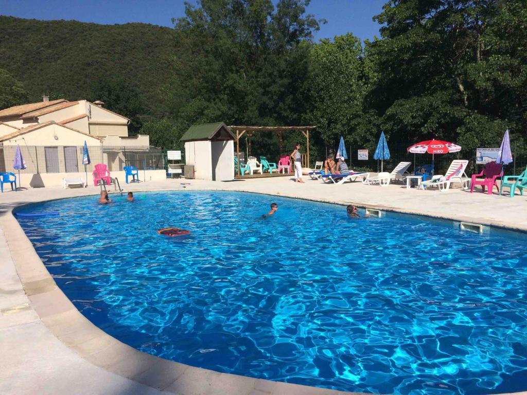 une grande piscine bleue avec des gens dedans dans l'établissement Camping Les Gorges de l'Hérault, à Sumène