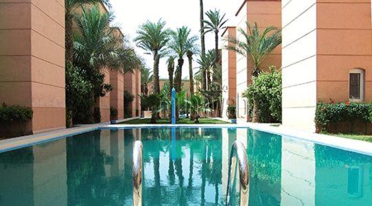 une piscine avec des palmiers et un bâtiment dans l'établissement Riad Naim, à Marrakech