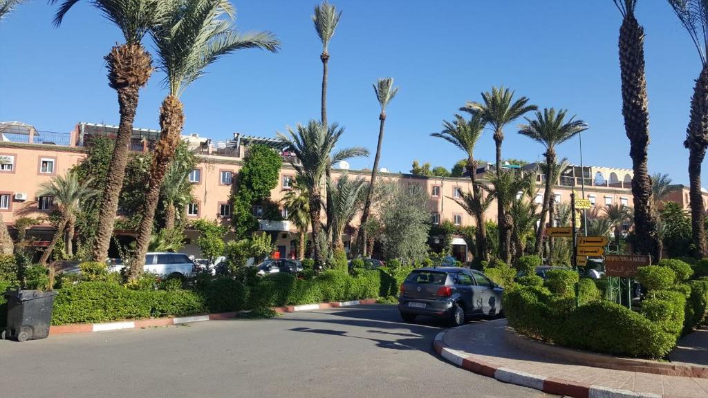 une voiture garée sur un parking avec des palmiers dans l'établissement Riad Naim, à Marrakech