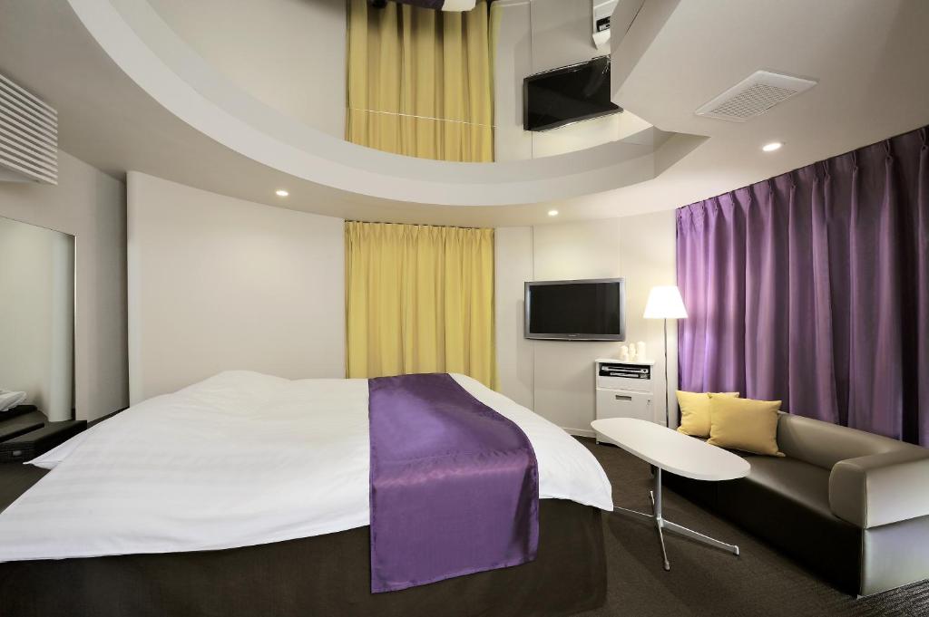 une chambre avec un grand lit et un canapé dans l'établissement Hotel Aqua Kiss Moriyama (Adult Only), à Moriyama