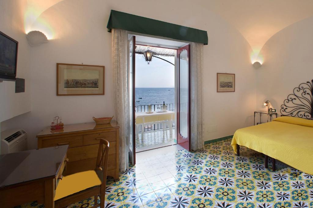 une chambre avec un lit et une vue sur l'océan dans l'établissement La Caravella di Positano - Relais, Beach & Residences, à Positano