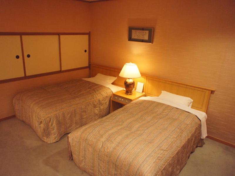 une chambre d'hôtel avec deux lits et une lampe dans l'établissement Usyounoie Sugiyama, à Gifu