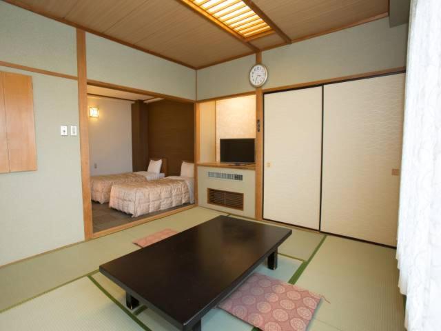 - une chambre avec un lit et une table dans l'établissement Ikaho Grand Hotel, à Shibukawa