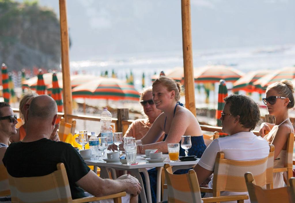 Un groupe de personnes assises à une table à la plage dans l'établissement Hotel Pupetto, à Positano