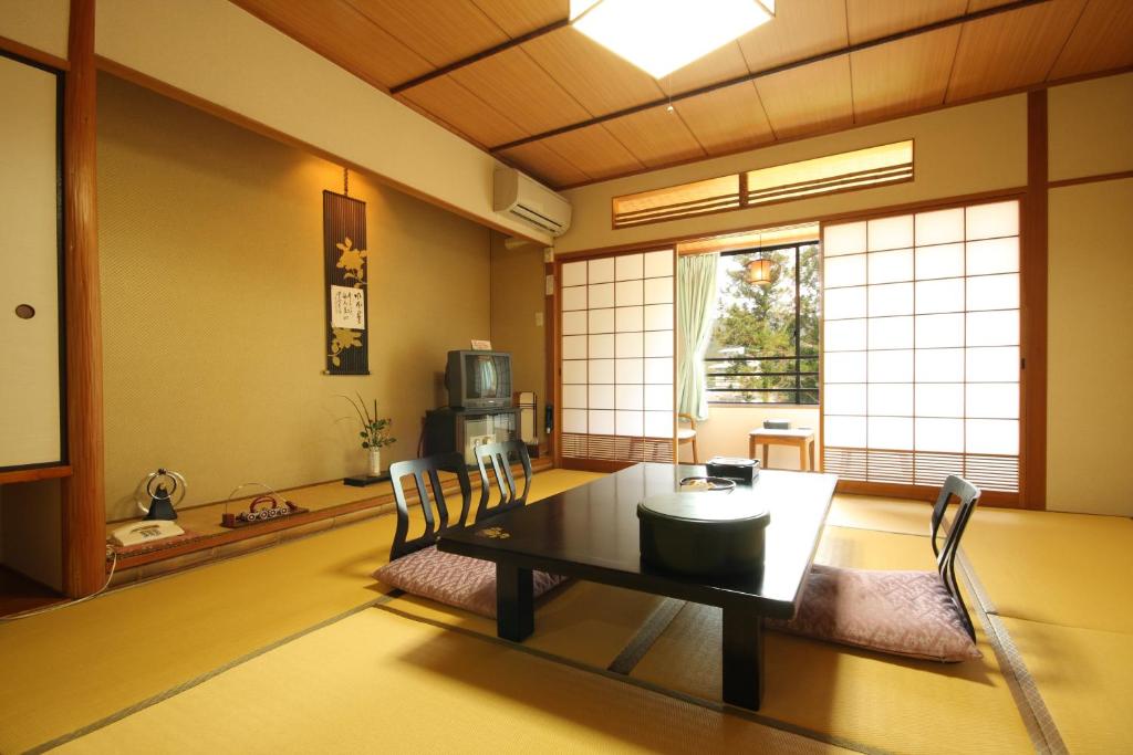 une salle à manger avec une table, des chaises et une télévision dans l'établissement Gyokusenkaku, à Nagato