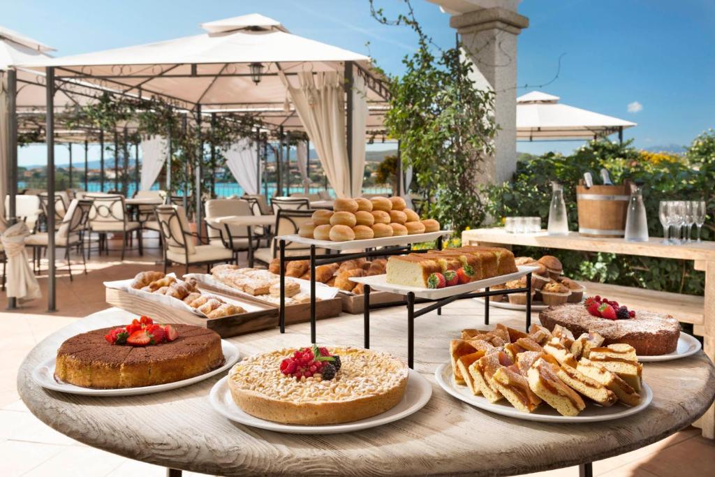 une table remplie de différents types de gâteaux et de pâtisseries dans l'établissement Gabbiano Azzurro Hotel & Suites, à Golfo Aranci
