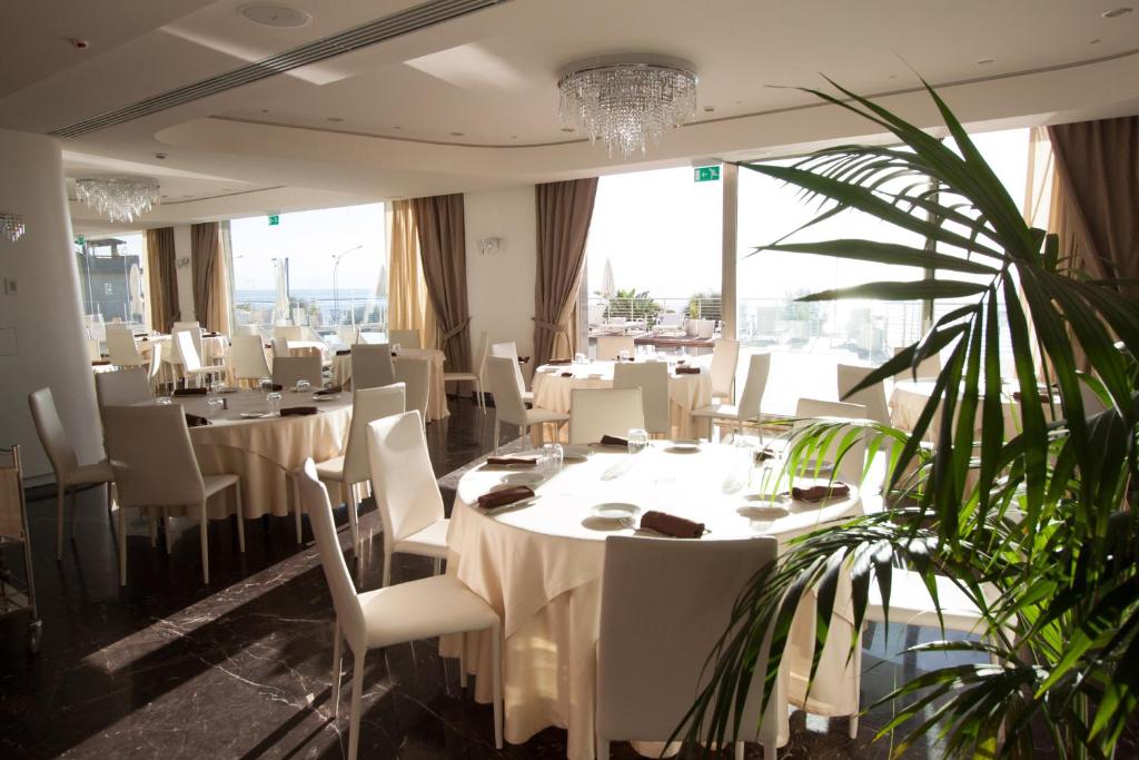 un restaurant avec des tables et des chaises blanches et une plante dans l'établissement Main Palace Hotel, à Roccalumera