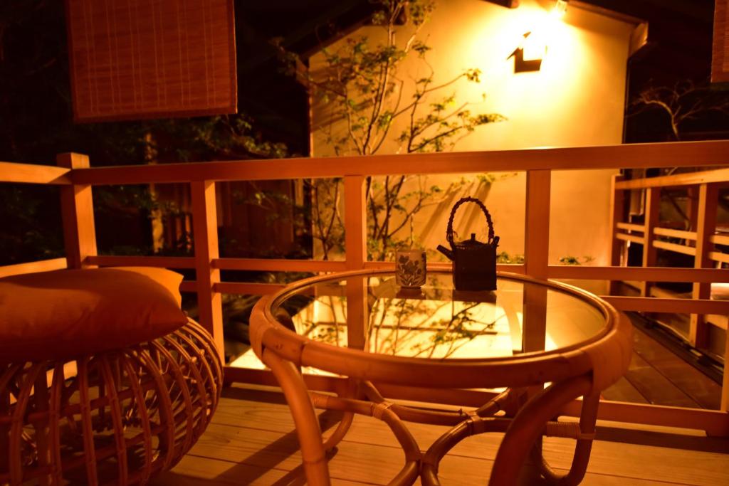 une table en verre et une chaise sur une terrasse la nuit dans l'établissement Yado Kiramachi, à Kyoto
