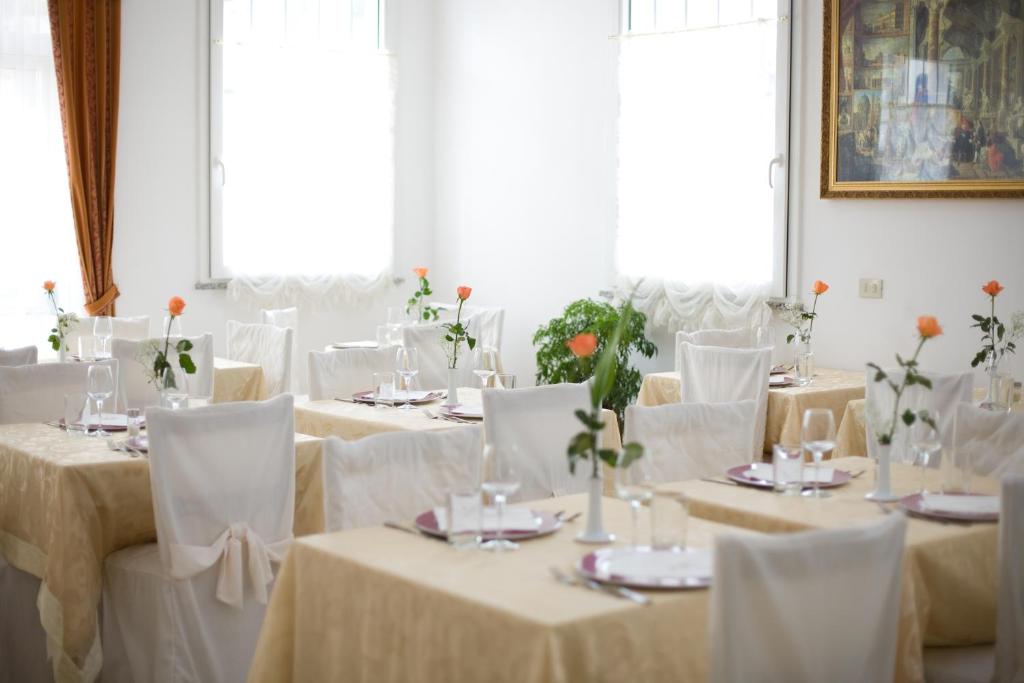 une salle remplie de tables avec des nappes blanches et des fleurs dans l'établissement Hotel Villa Pina, à Milano Marittima