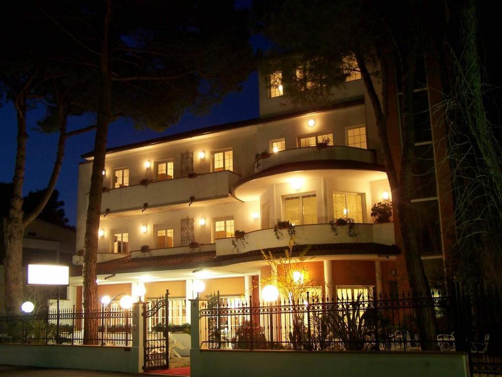 un grand bâtiment avec des lumières devant lui la nuit dans l'établissement Hotel Villa Pina, à Milano Marittima