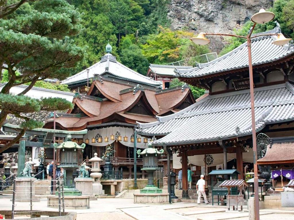 un grand bâtiment avec des toits bruns dans un parc dans l'établissement Shiroyama Ryokan, à Ikuma