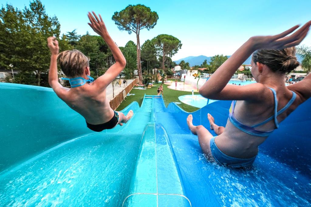 Deux garçons sautent d'un toboggan dans un parc aquatique dans l'établissement Camping Taxo Les Pins, à Argelès-sur-Mer