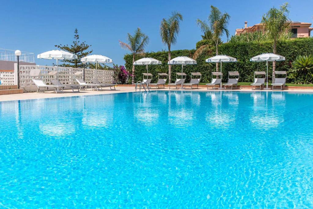 une grande piscine bleue avec chaises et parasols dans l'établissement Hotel Ferretti, à Diamante
