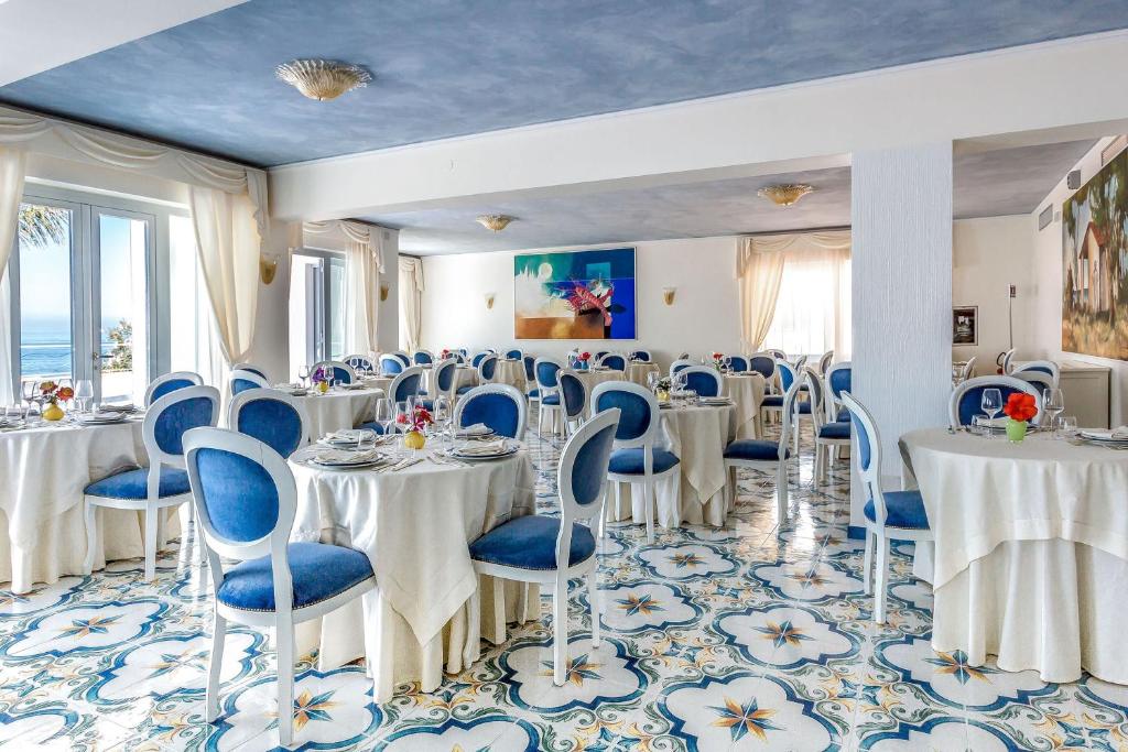 une salle de banquet avec des tables blanches et des chaises bleues dans l'établissement Hotel Ferretti, à Diamante