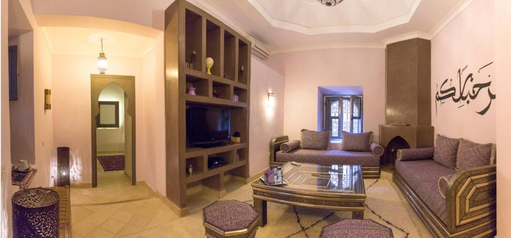 un salon avec un canapé et une télévision dans l'établissement Dar Andamaure, à Marrakech