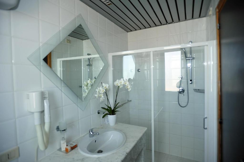 une salle de bain blanche avec lavabo et douche dans l'établissement Hotel Borgo Marina, à Rodi Garganico