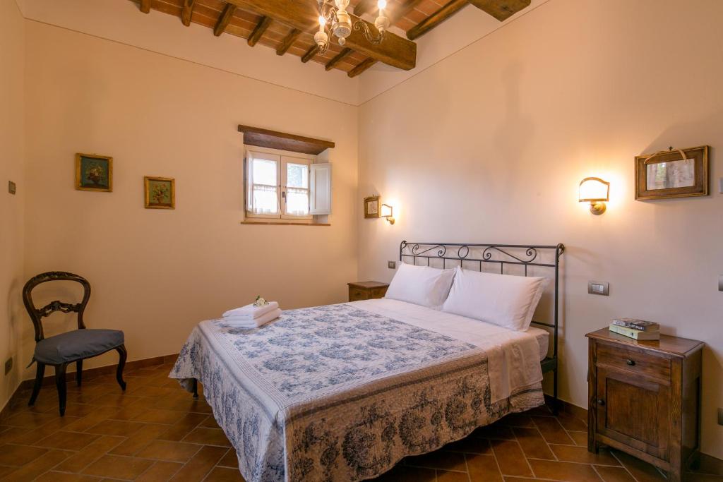 une chambre avec un lit, une chaise et une fenêtre dans l'établissement Villa Il Giardino di Diana, à Cortone