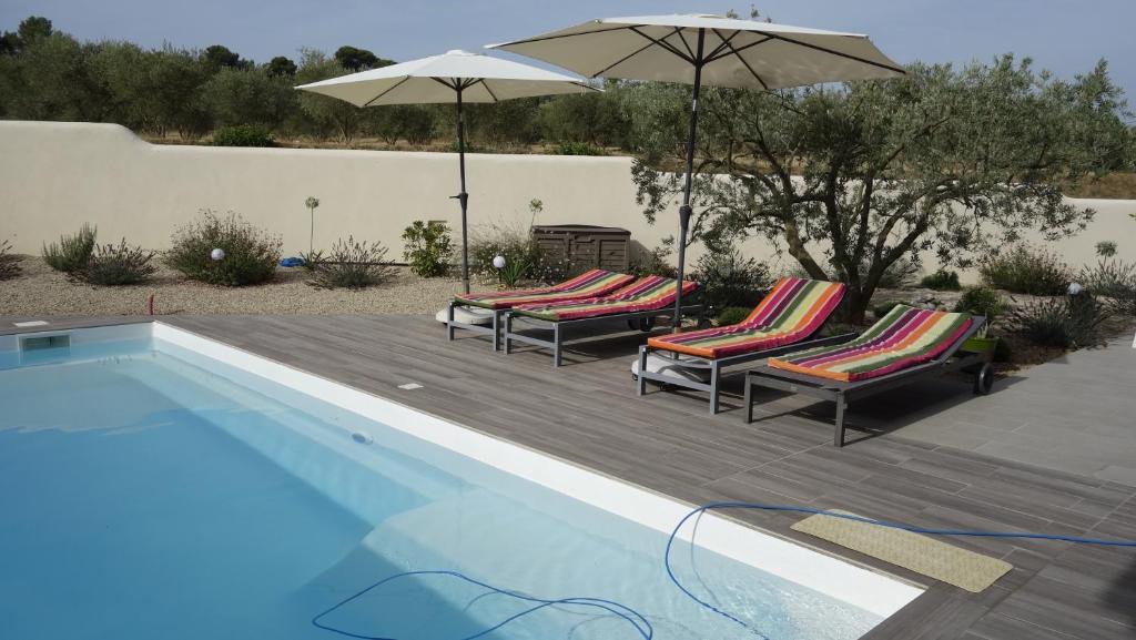 un groupe de chaises et de parasols à côté d'une piscine dans l'établissement Les Lavandins-Gite Magali, à Saint-Rémy-de-Provence 24 autres photos