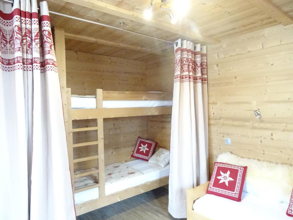 Cette chambre en bois comprend 2 lits superposés et des rideaux. dans l'établissement Apart'hotel & Spa "La Destière", à La Giettaz