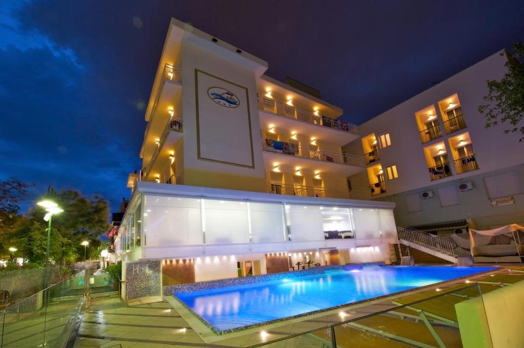 un hôtel avec une piscine devant un bâtiment dans l'établissement Hotel Lido, à Cattolica