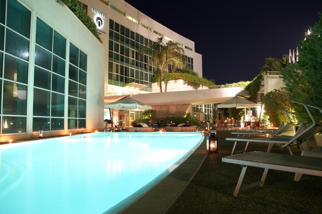 une piscine devant un immeuble la nuit dans l'établissement Nicotel Bisceglie, à Bisceglie