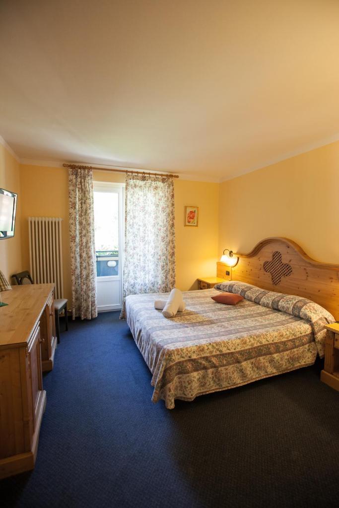 une chambre d'hôtel avec un grand lit et une fenêtre dans l'établissement Garden Hotel Bellariva, à Molveno
