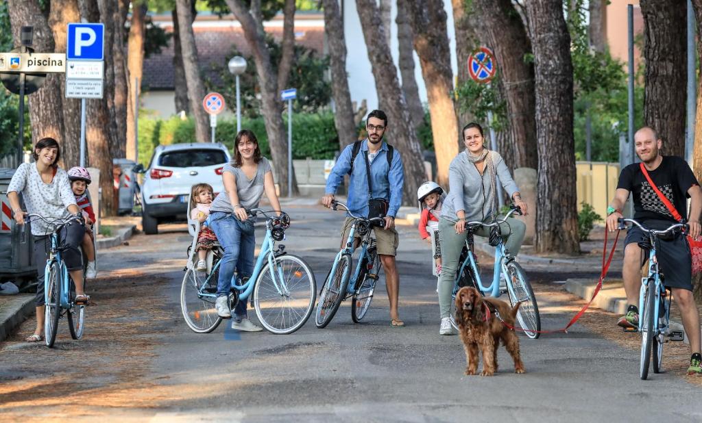 un groupe de personnes voyageant à vélo dans une rue avec un chien dans l'établissement Hotel Riziana, à Cervia