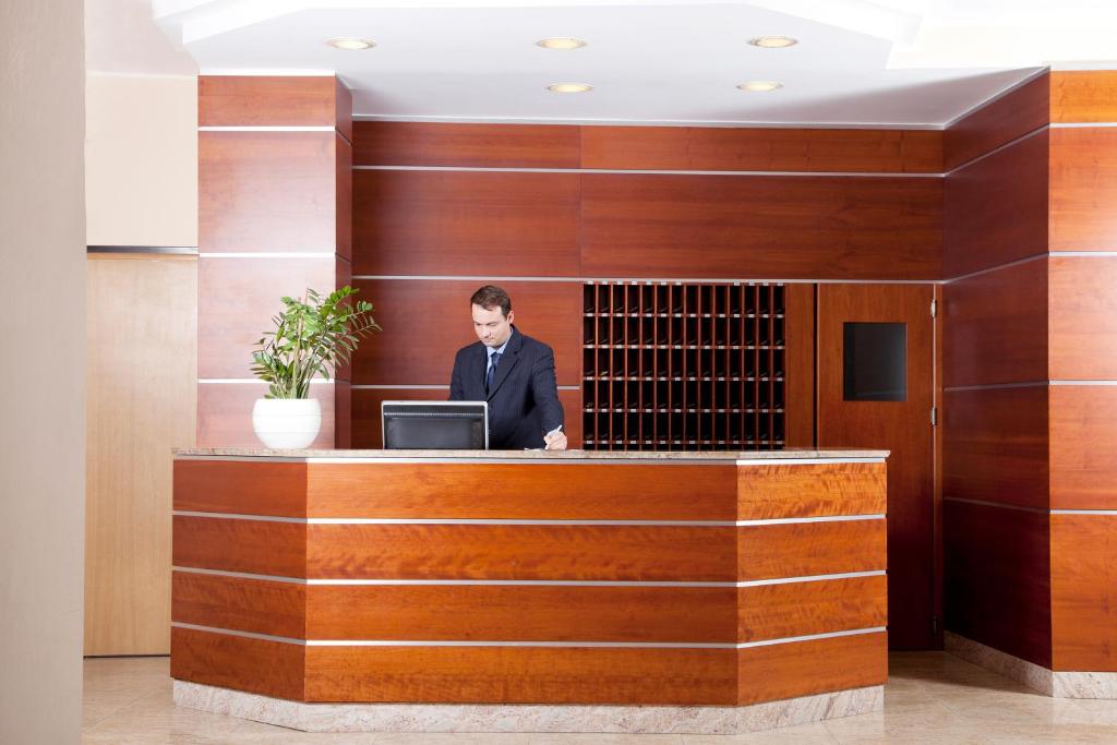 un homme assis à la réception avec un ordinateur portable dans l'établissement Hotel Meridiano, à Termoli