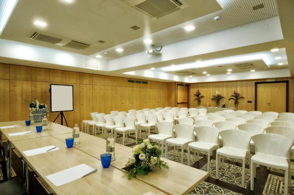 une salle de conférence avec des chaises blanches et un podium dans l'établissement Mare Hotel, à Savone 55 autres photos
