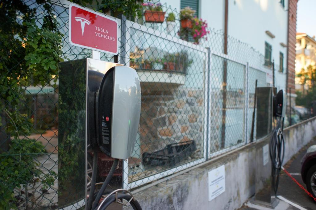 un téléphone payant sur un trottoir à côté d'une clôture dans l'établissement Hotel Garden Lido, à Loano