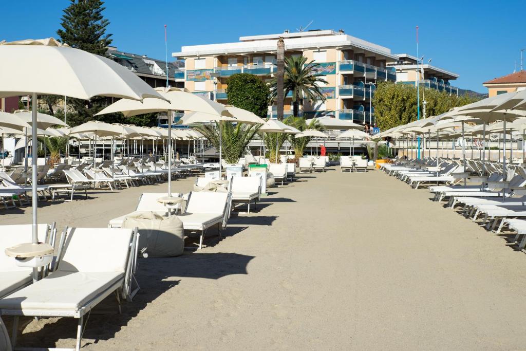 une rangée de chaises longues et de parasols sur une plage dans l'établissement Hotel Garden Lido, à Loano 61 autres photos