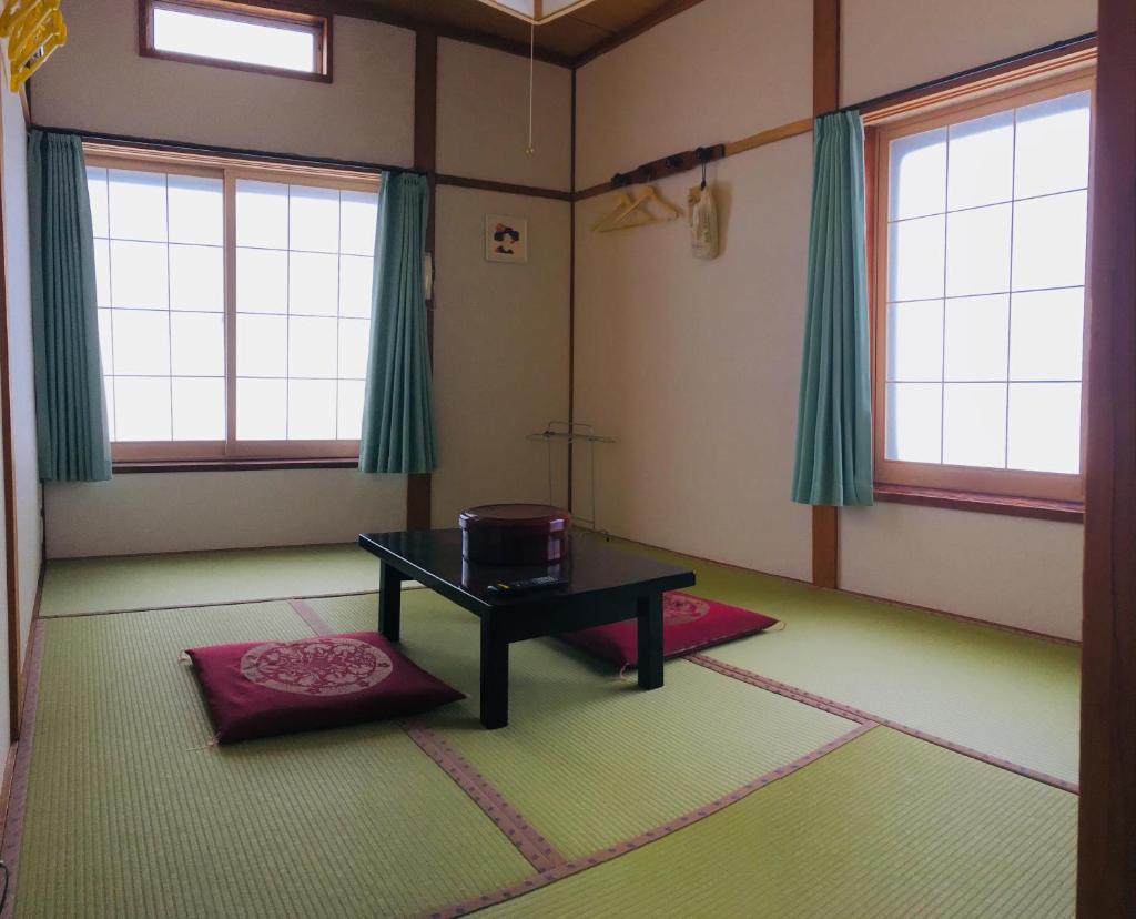 une chambre avec une table et deux fenêtres dans l'établissement Yamakyuso, à Otari