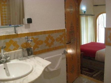 La salle de bains est pourvue d'un lavabo et d'une baignoire à côté d'un lit. dans l'établissement Dar Aida, à Rabat