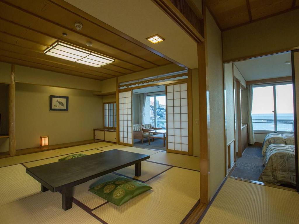 une chambre avec une table et un salon avec vue dans l'établissement Hotel Oonoya, à Atami
