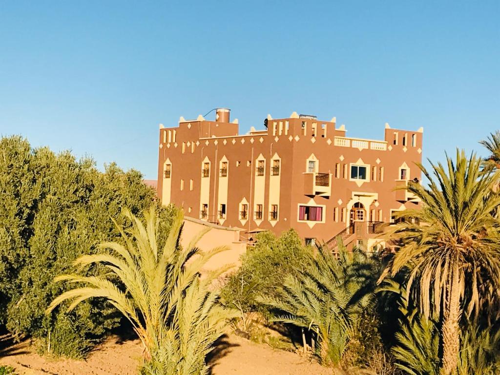 un grand bâtiment avec des palmiers devant dans l'établissement Riad Dar Bab Todra, à Tinghir