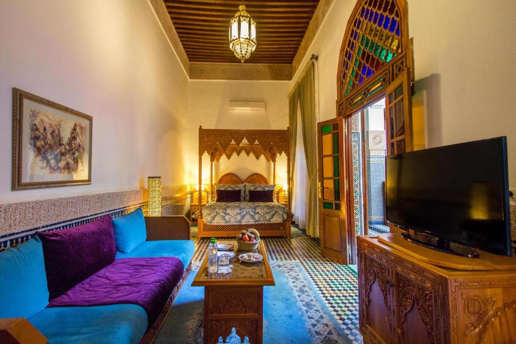 un salon avec un canapé bleu et une télévision dans l'établissement Riad Myra, à Fès