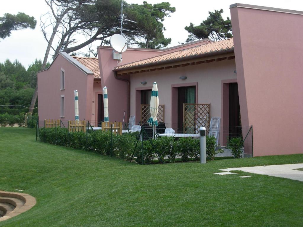 une maison rose avec des chaises et des parasols dans une cour dans l'établissement Miramare Resort, à Tirrenia 12 autres photos
