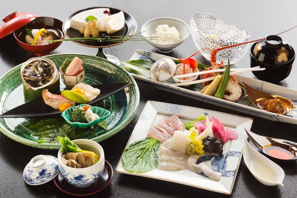 une table avec plusieurs assiettes de nourriture dessus dans l'établissement Ryokan KANADE, à Kyoto