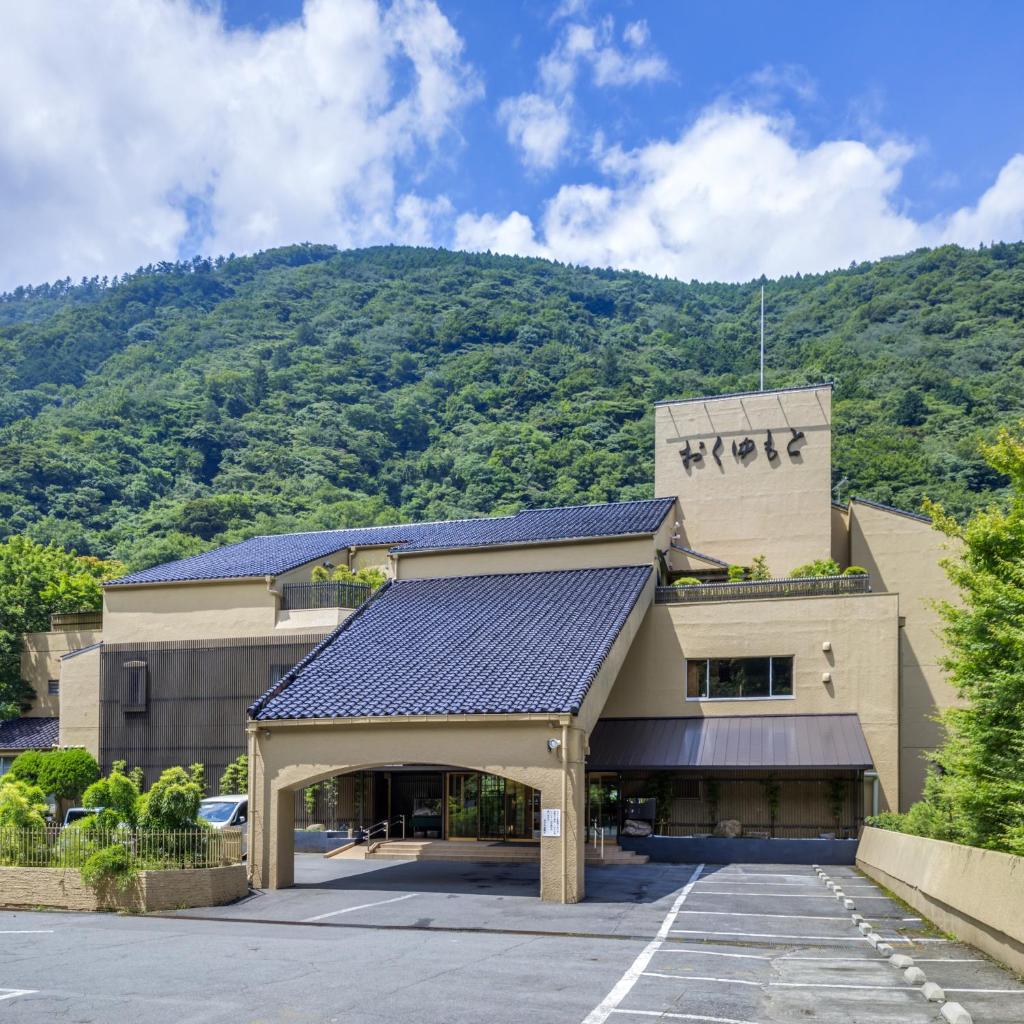un bâtiment d'hôtel avec une montagne en arrière-plan dans l'établissement Hotel Okuyumoto, à Hakone