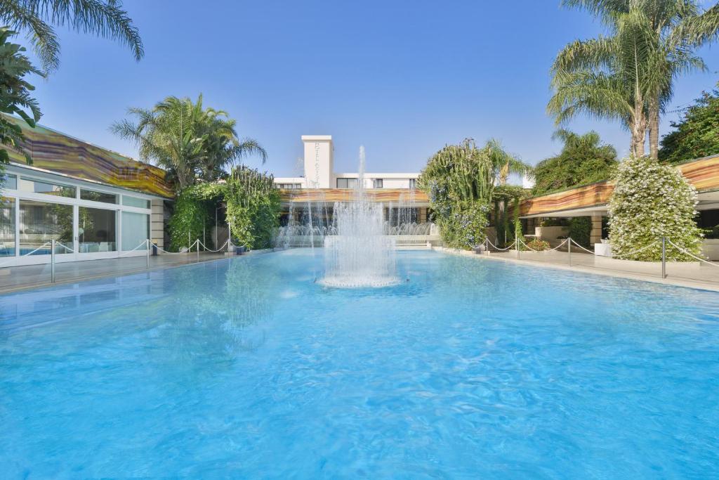 une grande piscine avec une fontaine en face d'un bâtiment dans l'établissement Hotel Ariston, à Paestum