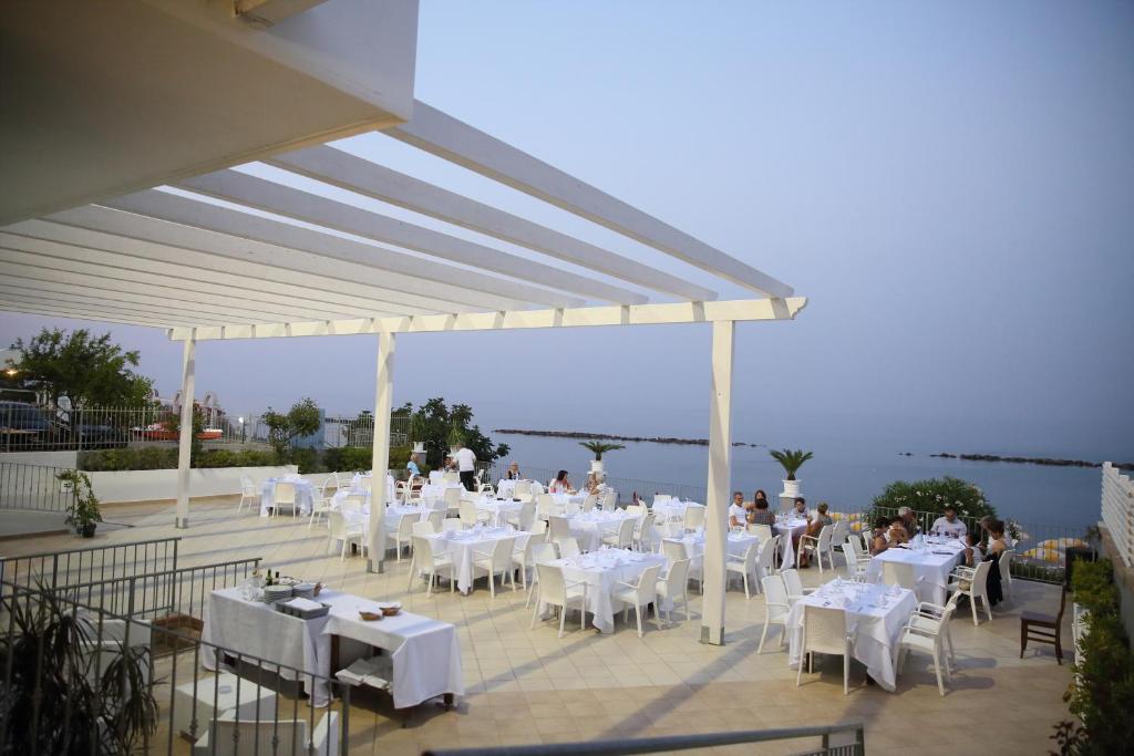un restaurant avec des tables et des chaises blanches et l'eau dans l'établissement Hotel Dolce Stella, à Torre Melissa