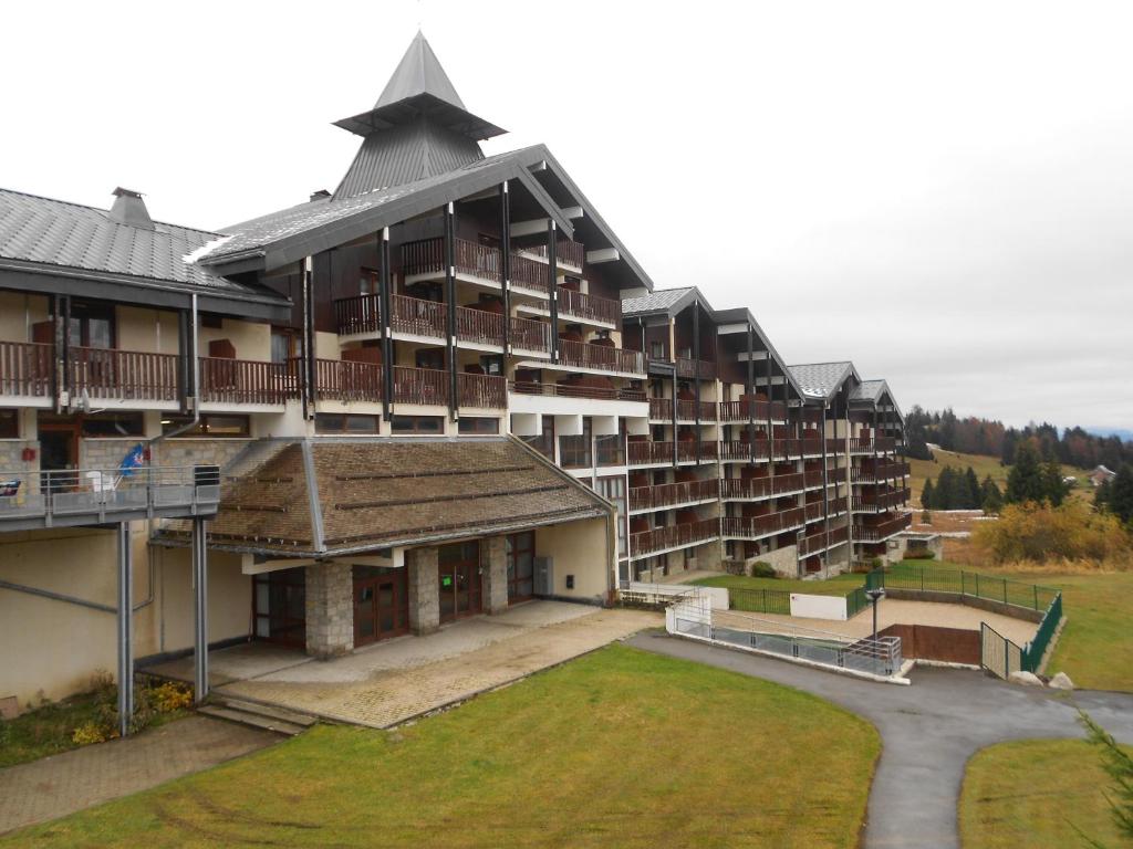 un grand immeuble d'appartements avec une pelouse devant lui dans l'établissement Prazdelys, à Praz de Lys - Sommand