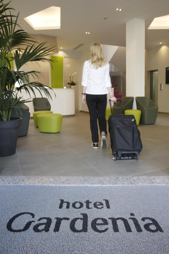 une femme traversant le hall d'un hôtel avec une valise dans l'établissement Hotel Gardenia, à Lido di Jesolo