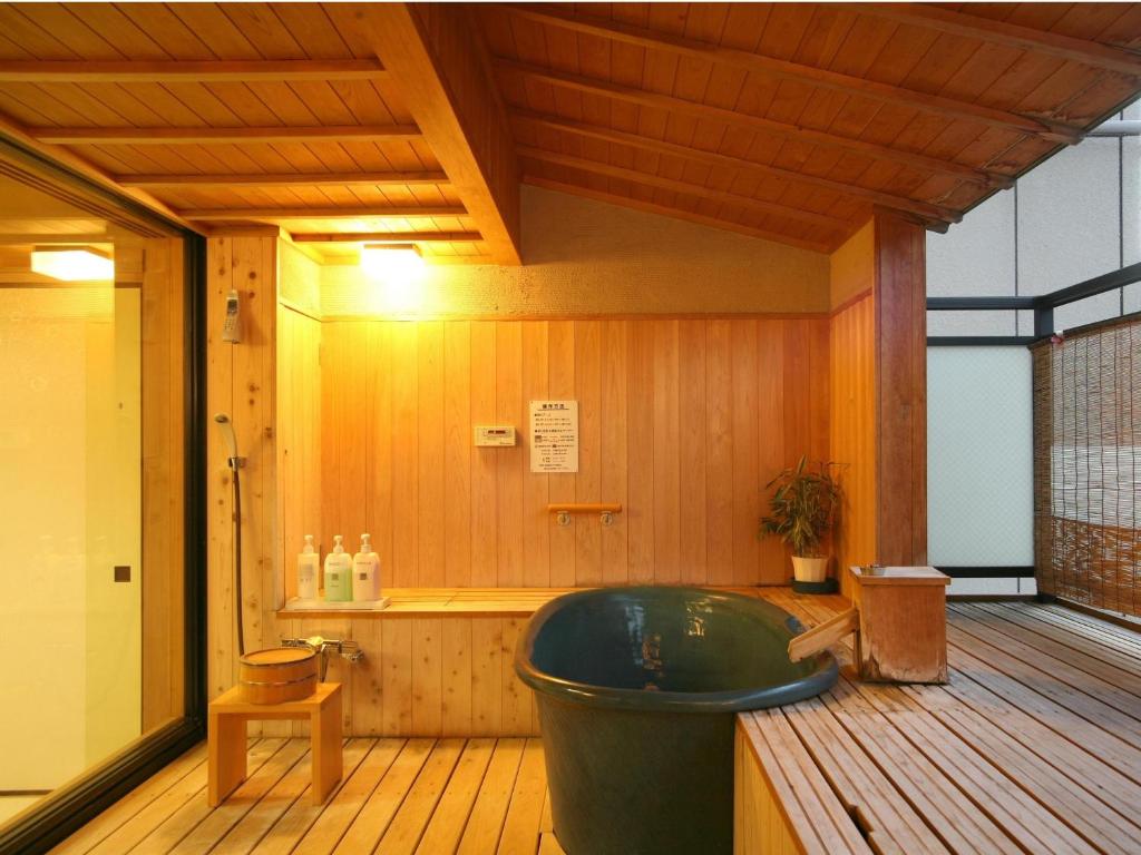 La salle de bains est pourvue d'une baignoire verte et de parquet. dans l'établissement Kotohira Onsen Kotosankaku, à Kotohira